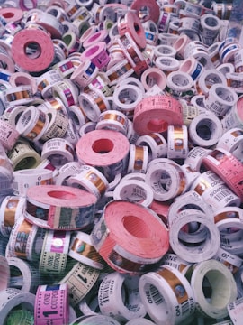 A collection of colorful tickets or coupons rolled into cylinders, with various denominations and text visible on each roll. The tickets are stacked in a chaotic and overlapping manner, showcasing a range of colors and patterns.