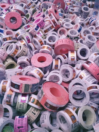 A collection of colorful tickets or coupons rolled into cylinders, with various denominations and text visible on each roll. The tickets are stacked in a chaotic and overlapping manner, showcasing a range of colors and patterns.
