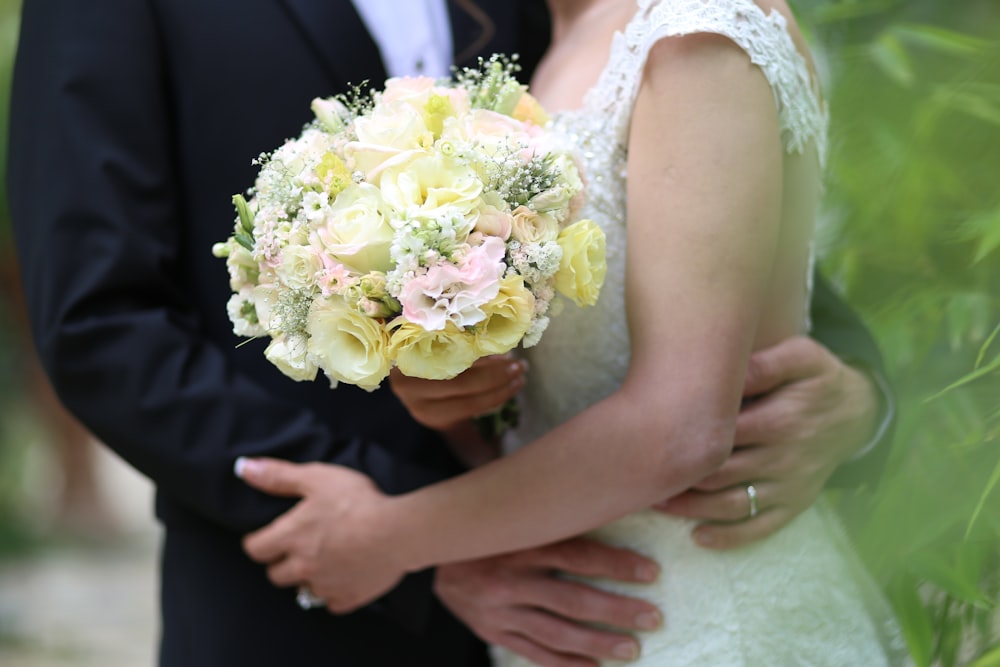 woman in white floral wedding dress holding bouquet of white roses