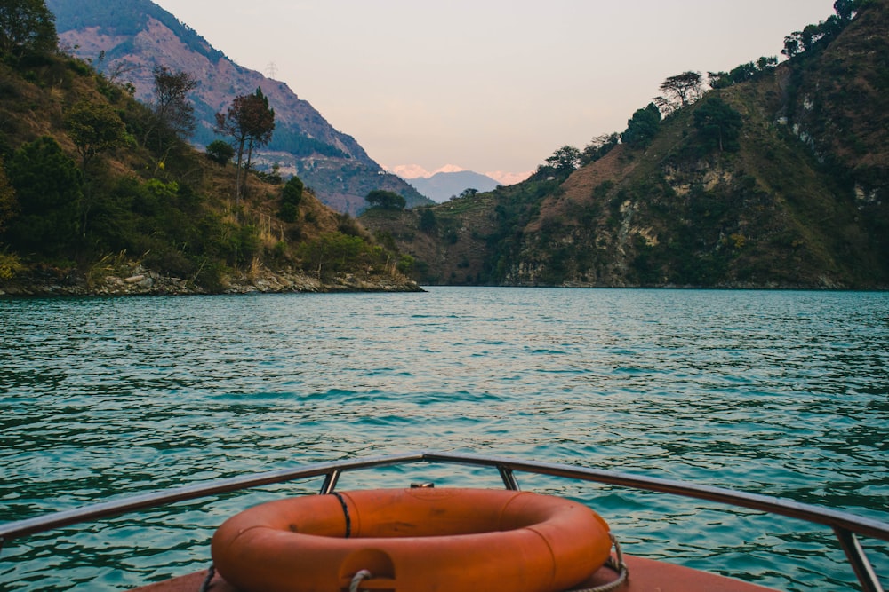 brown boat on water near mountain during daytime