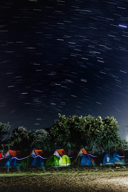 Colorful tents set up under a starry night sky.