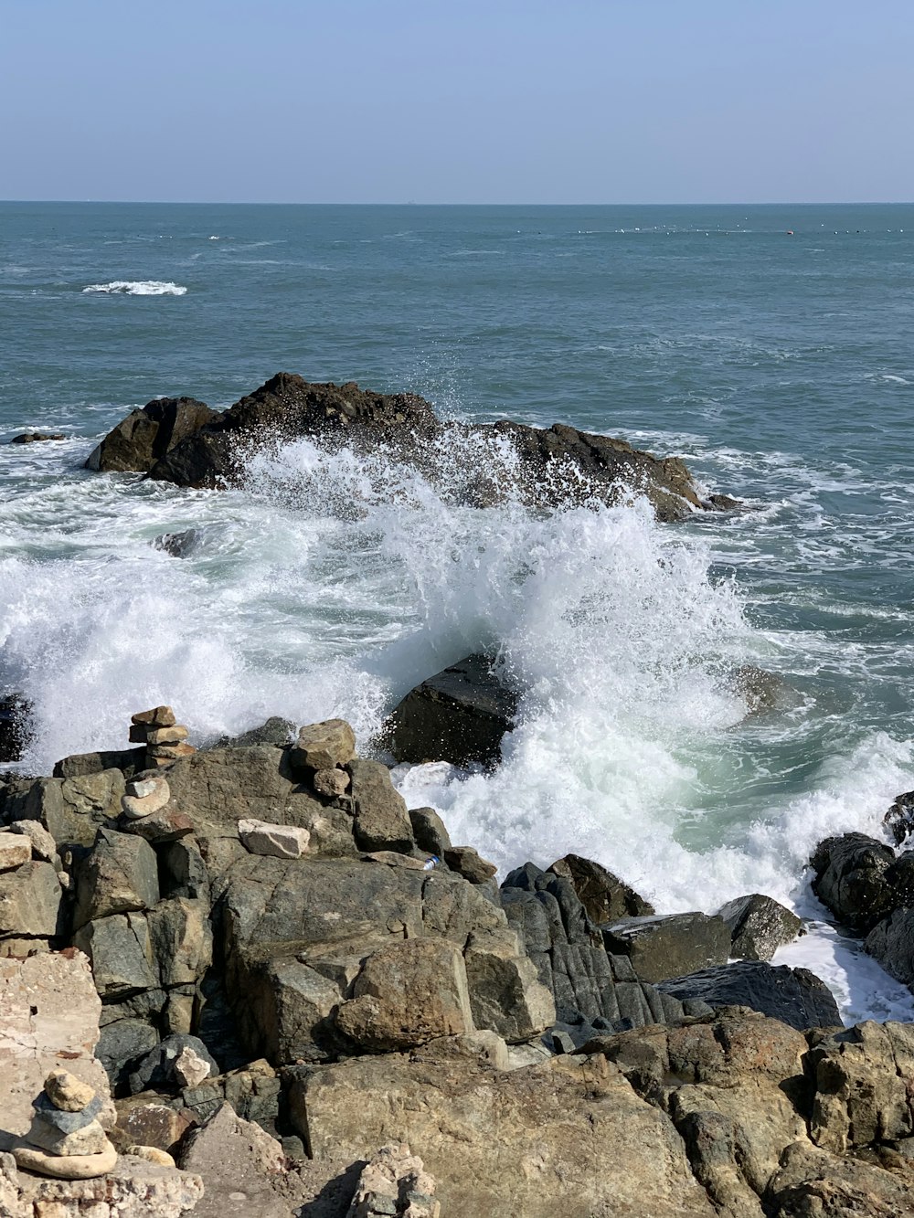 日中の海の波のある茶色の岩だらけの海岸