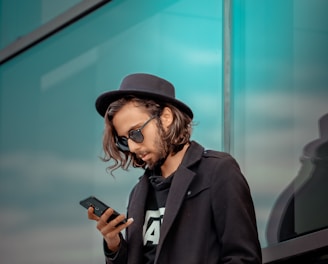 man in black coat holding smartphone