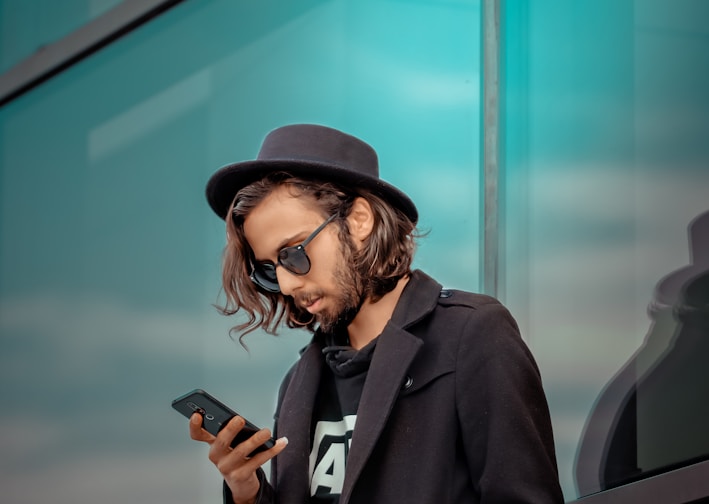 man in black coat holding smartphone