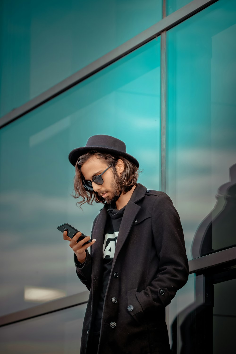 man in black coat holding smartphone