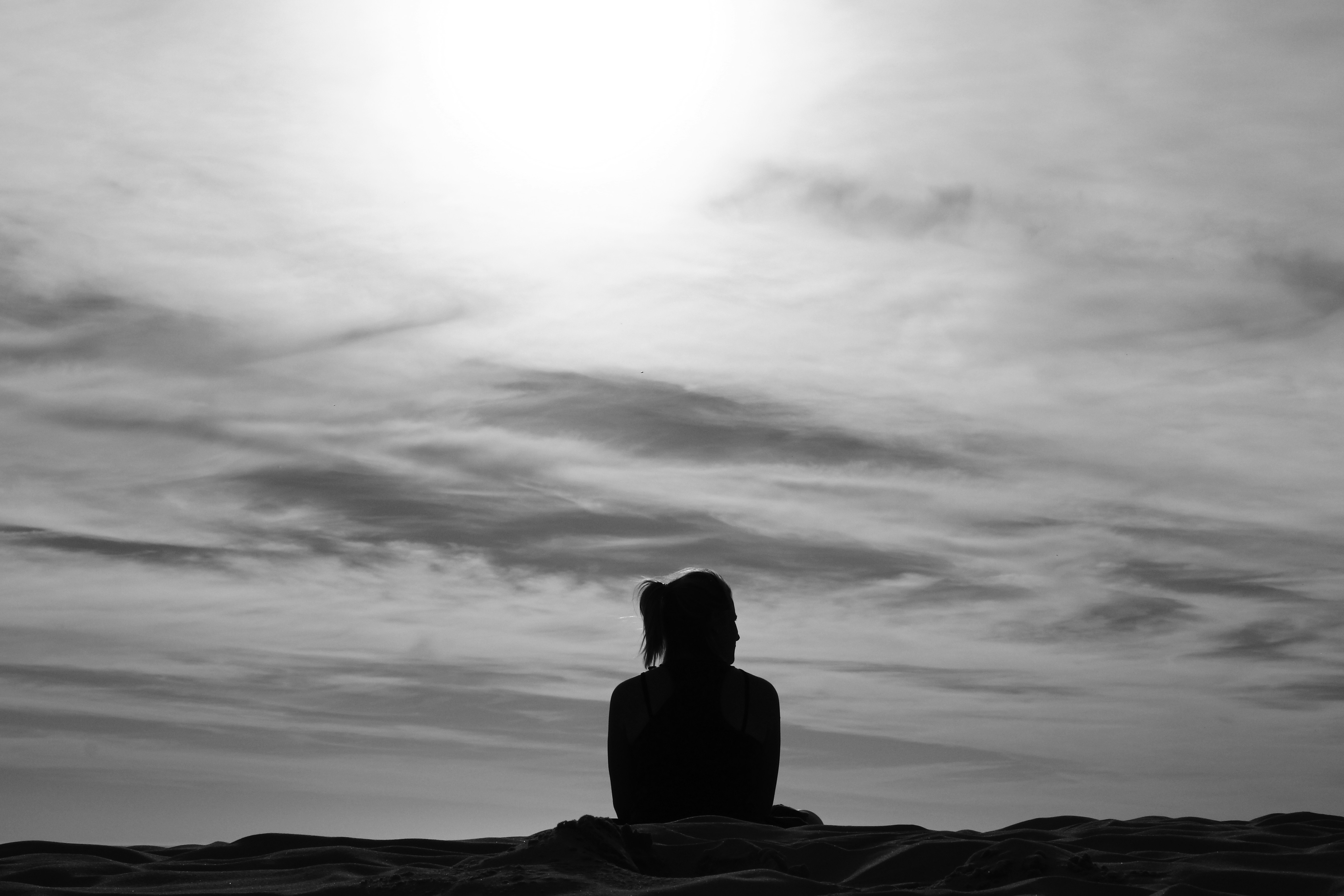 A woman sitting on the empty beach thinking