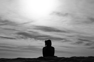 silhouette of woman sitting on rock