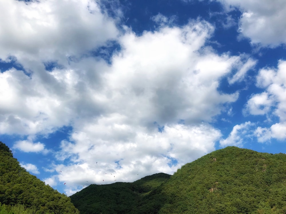 green mountain under white clouds and blue sky during daytime