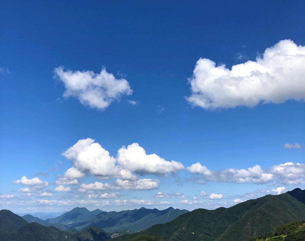 green mountains under blue sky and white clouds during daytime