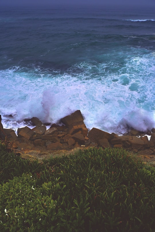 brown rocks near body of water during daytime in Colares Portugal