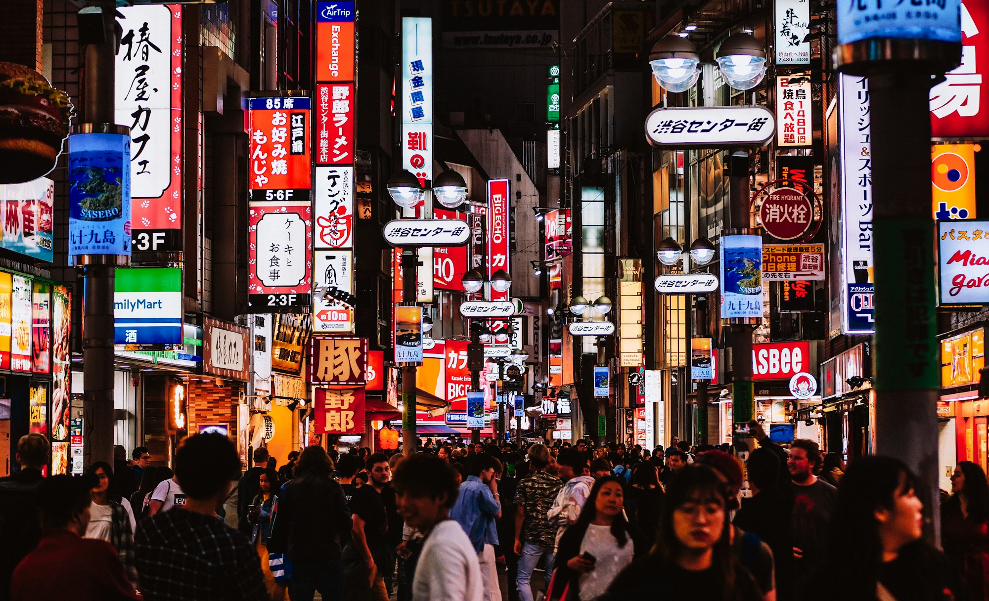 Night shot of a crowded street in Tokyo full of neon signs.