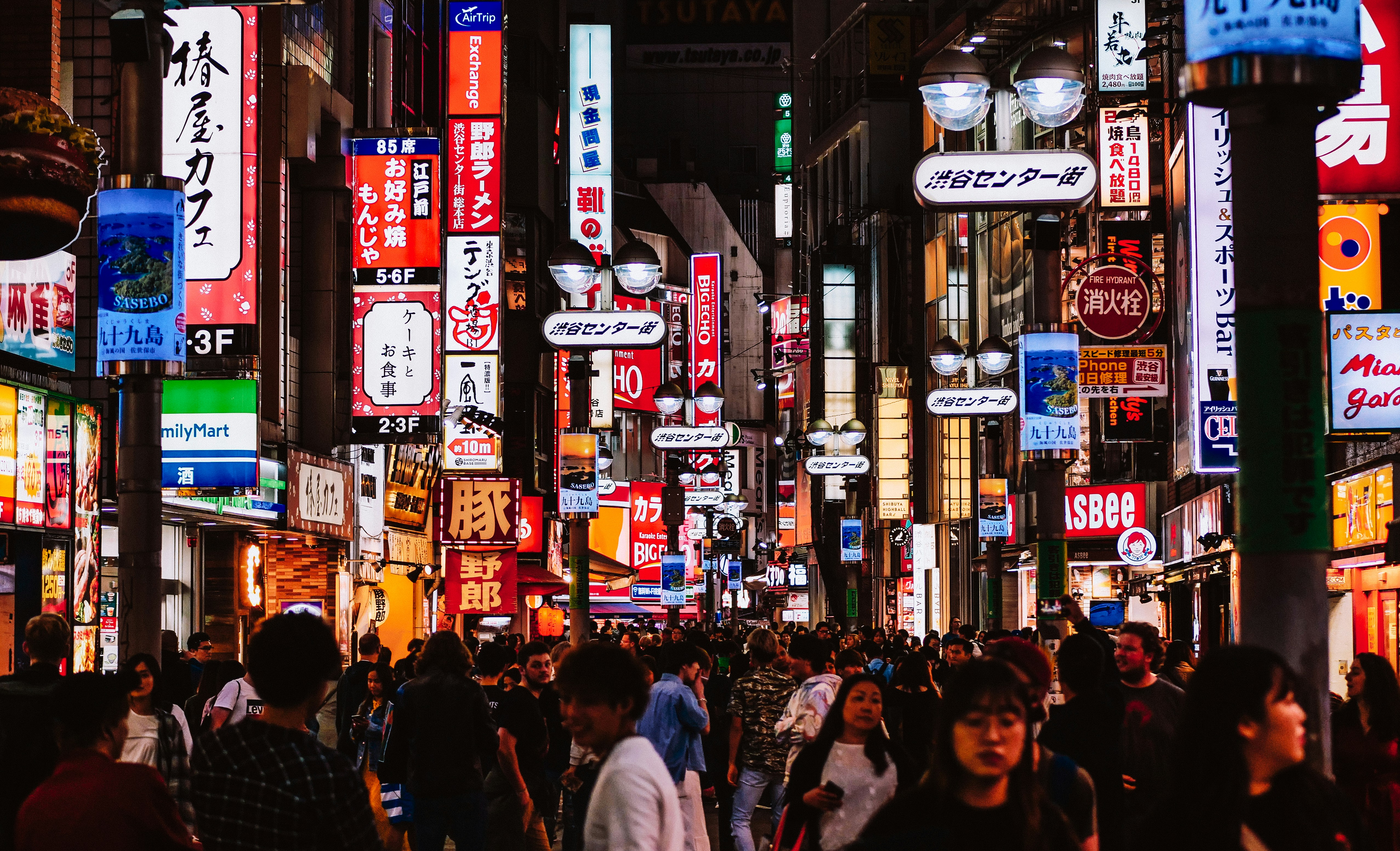 Night shot of a crowded street in Tokyo full of neon signs.