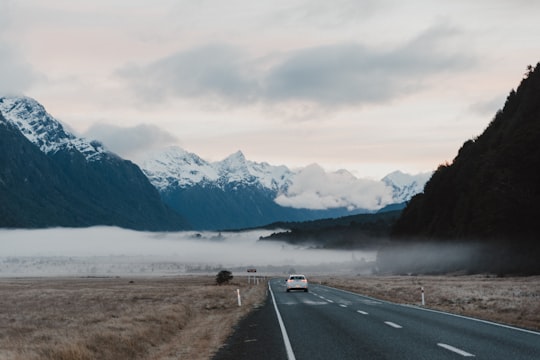 white car on road near snow covered mountain during daytime in Fiordland National Park New Zealand