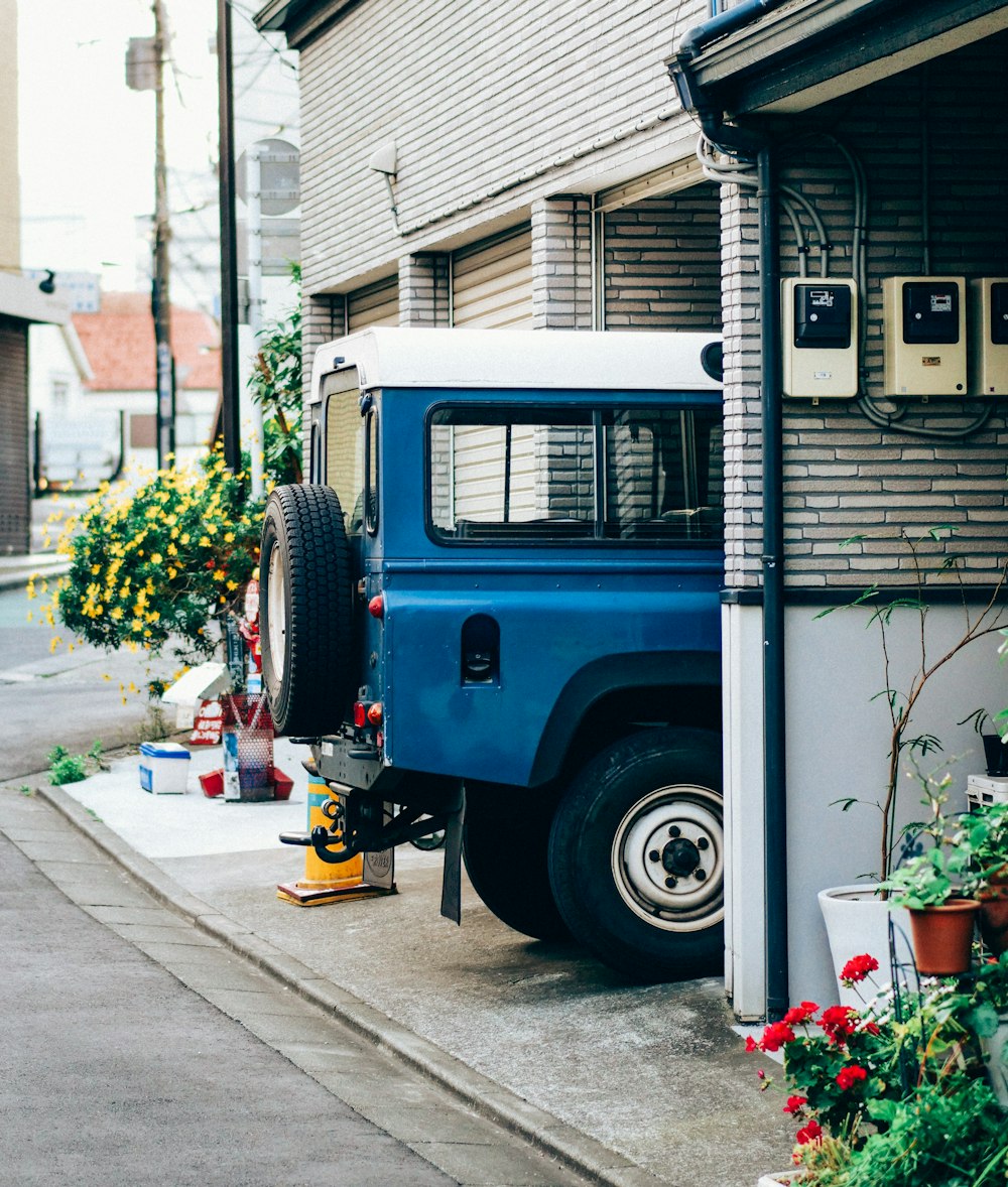 Blau-weißer Jeep Wrangler tagsüber auf dem Bürgersteig geparkt