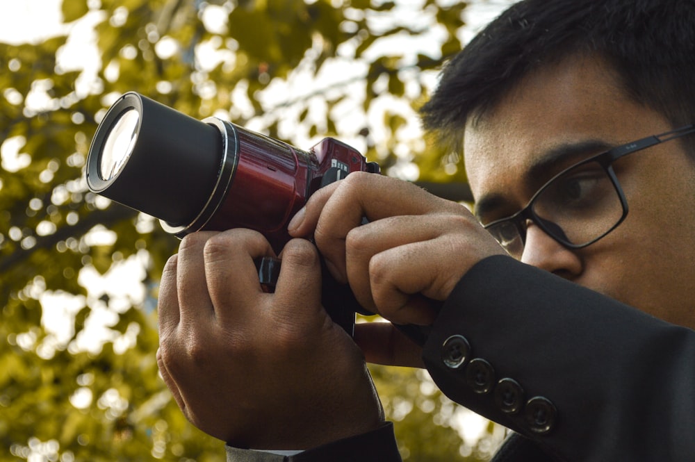 person holding black and red camera during daytime