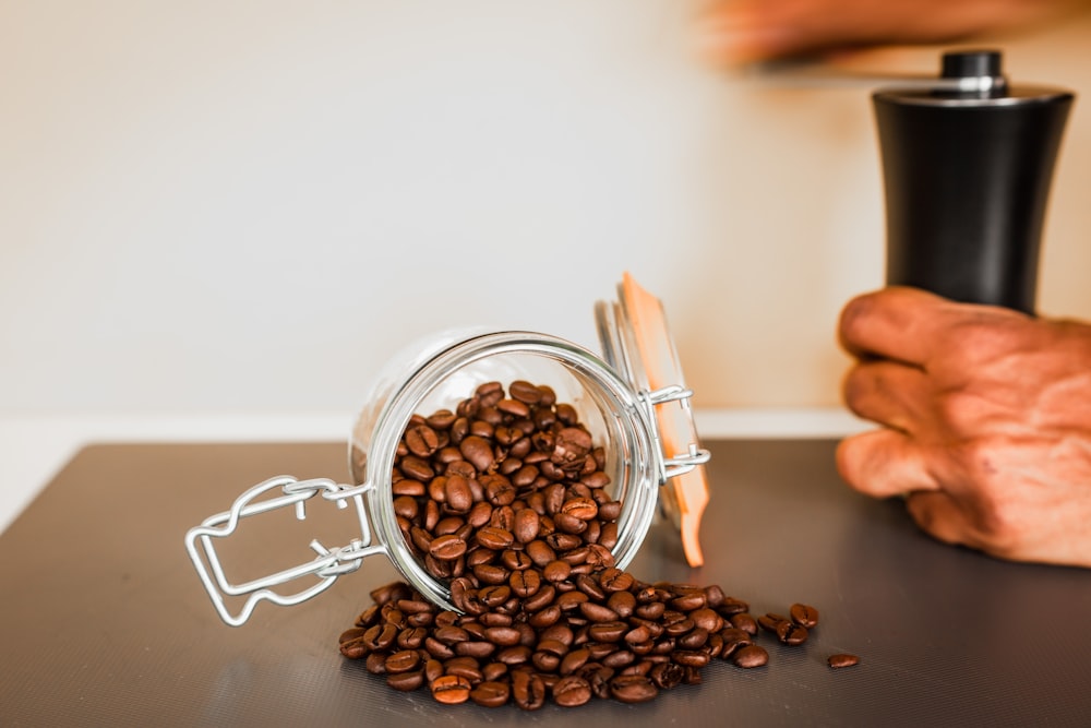 person holding white plastic cup with coffee beans