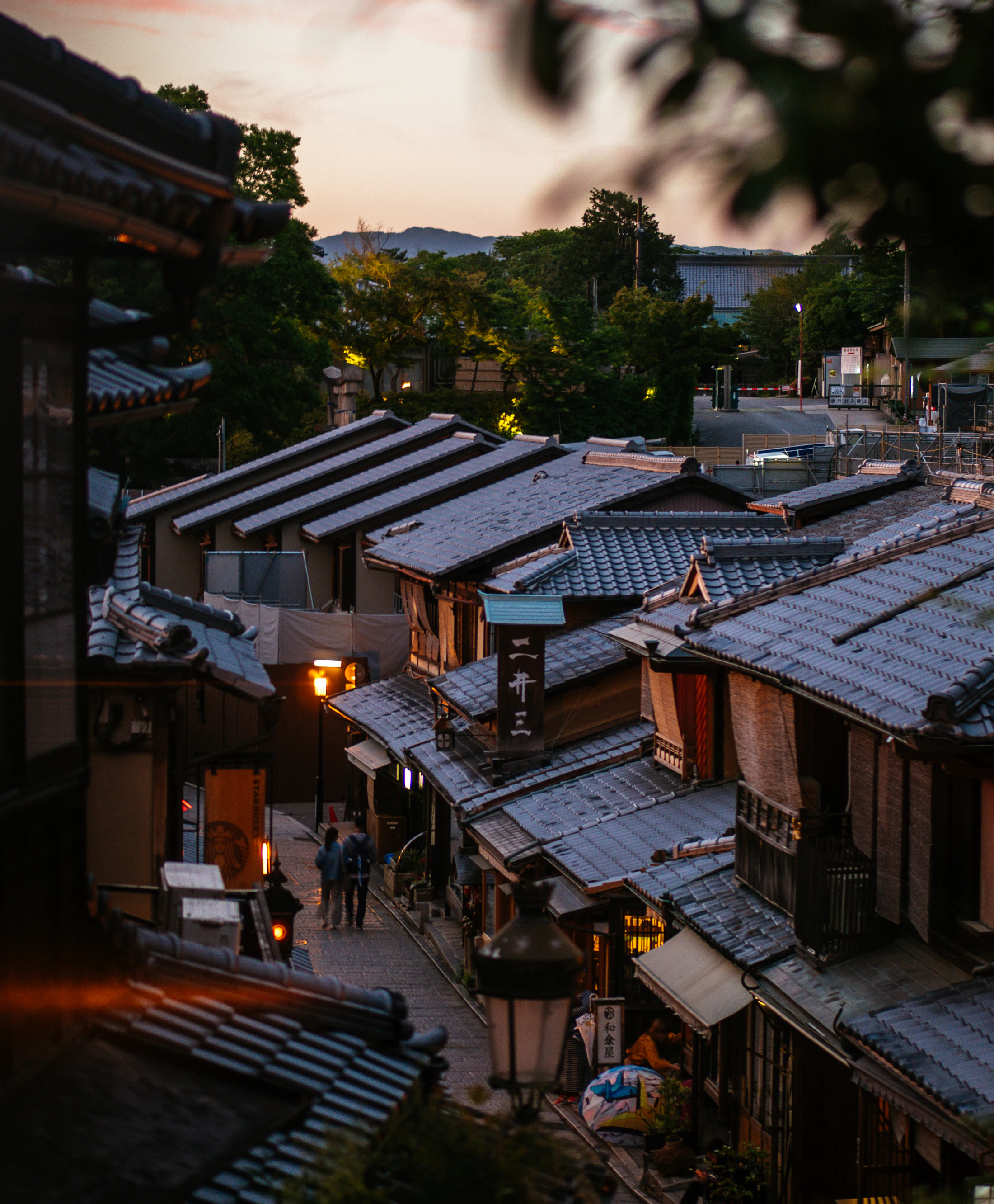 Tiled rooftops of old Kyoto houses glowing at sunset