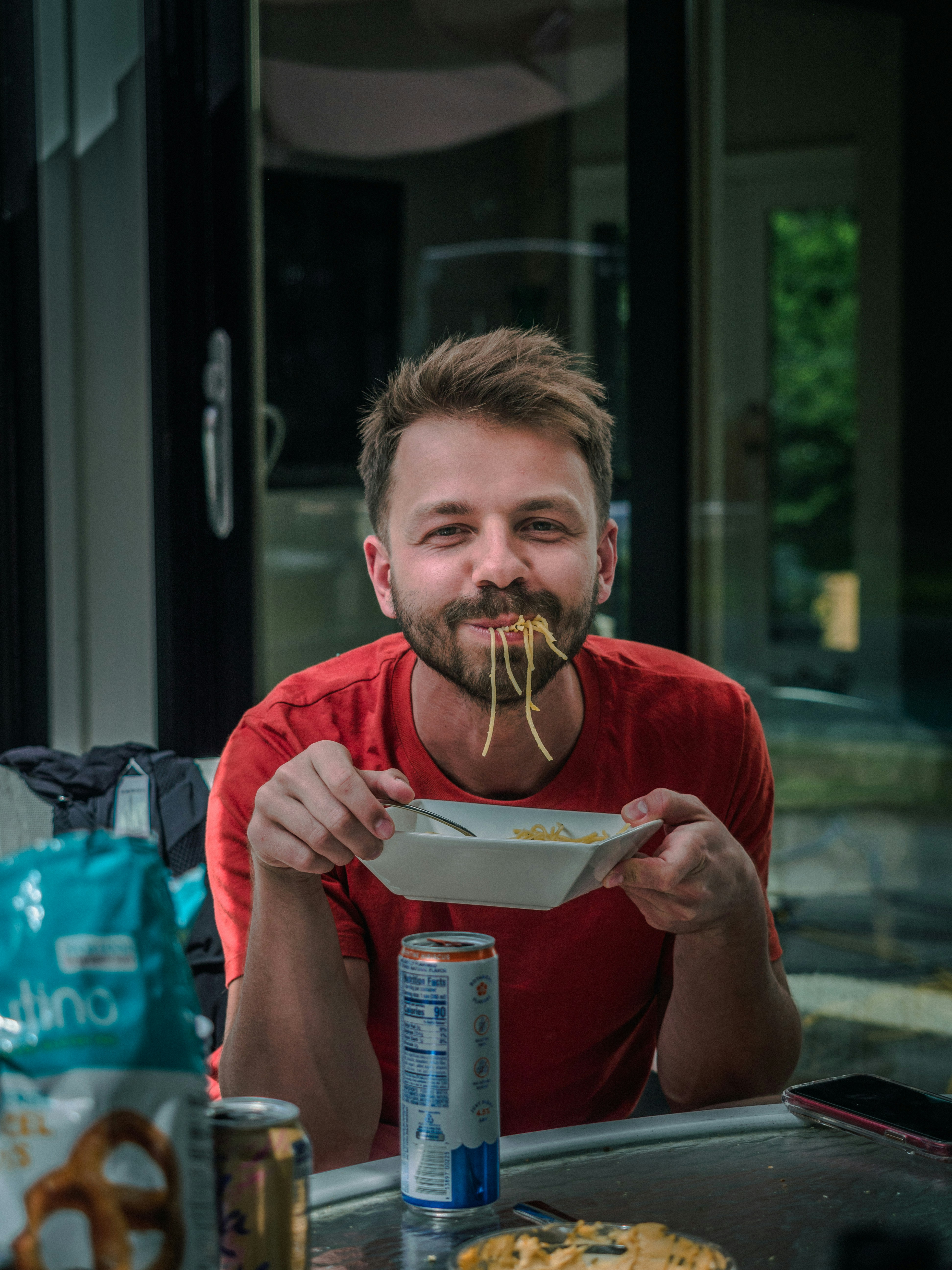 great photo recipe,how to photograph a guy eating pasta. ; man in red crew neck t-shirt holding white and red labeled can