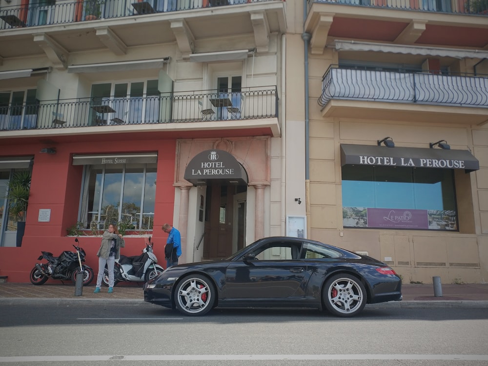 black coupe parked beside brown concrete building during daytime