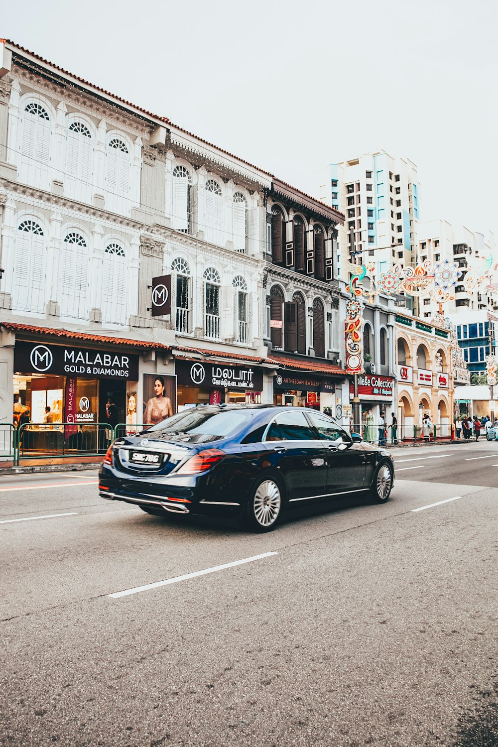 black sedan parked in front of white concrete building during daytime