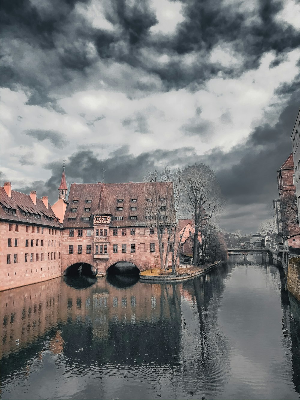 brown concrete building near body of water under cloudy sky during daytime