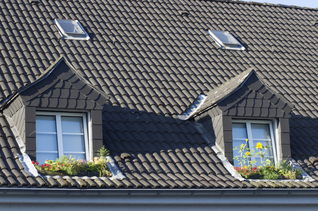 Dark tile roof with two dormer windows, skylights and flower boxes