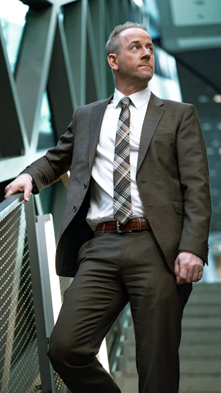 man in black suit sitting on white bench notning behind him
