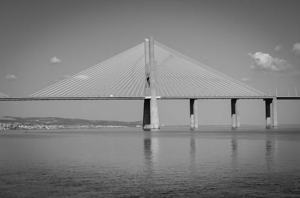 grayscale photo of bridge under cloudy sky