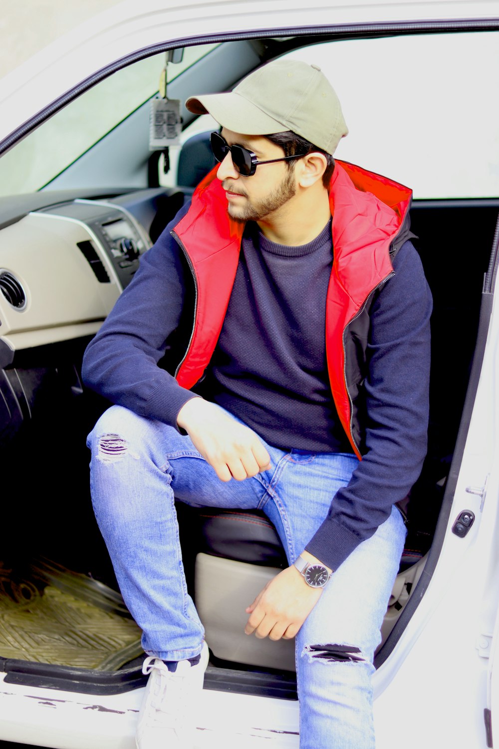 woman in red zip up jacket and blue denim jeans sitting on car seat