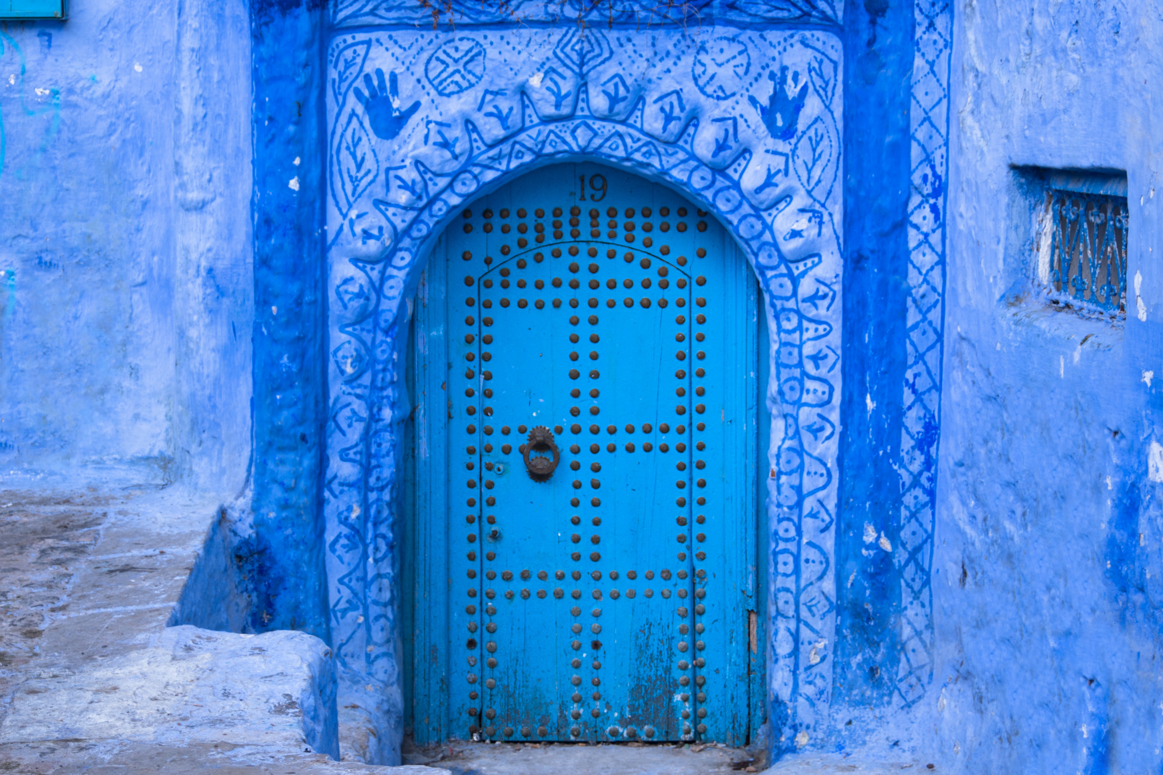 una porta blu con decorazioni orientali in un muro azzurro (nell'articolo le informazioni utili per un viaggio in Marocco)