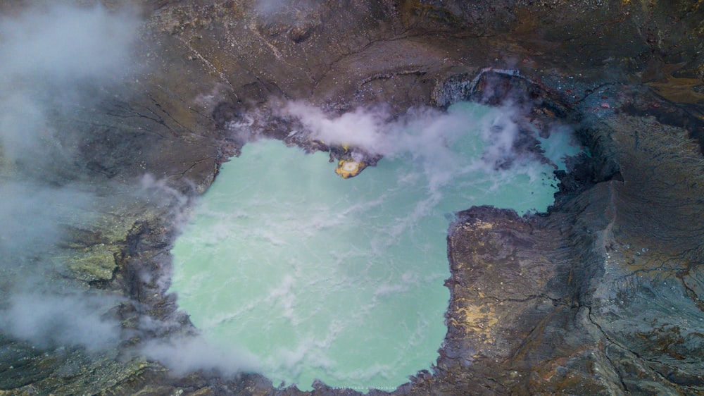 person in yellow shirt sitting on rock formation near body of water during daytime