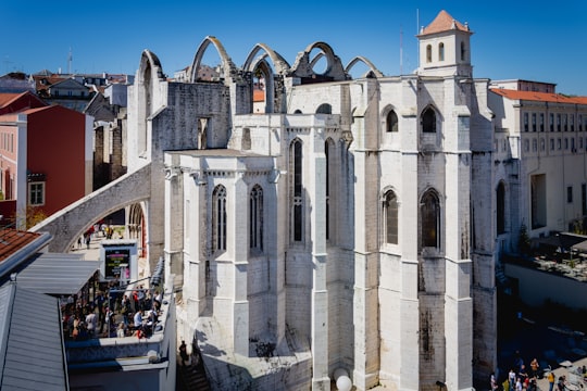 people walking on sidewalk near brown concrete building during daytime in Carmo Convent Portugal