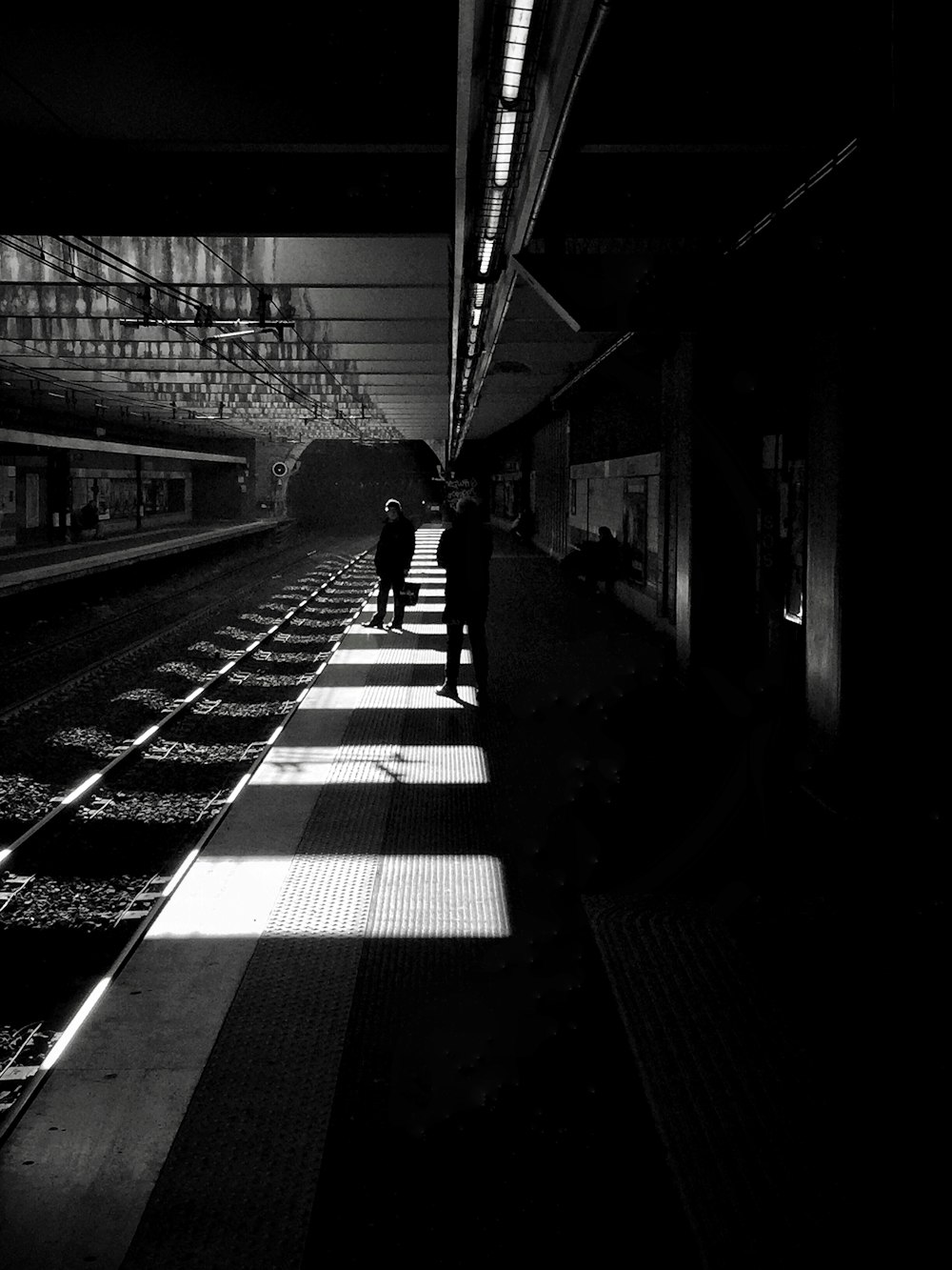 Graustufenfoto eines Mannes, der auf dem Bahnhof spazieren geht