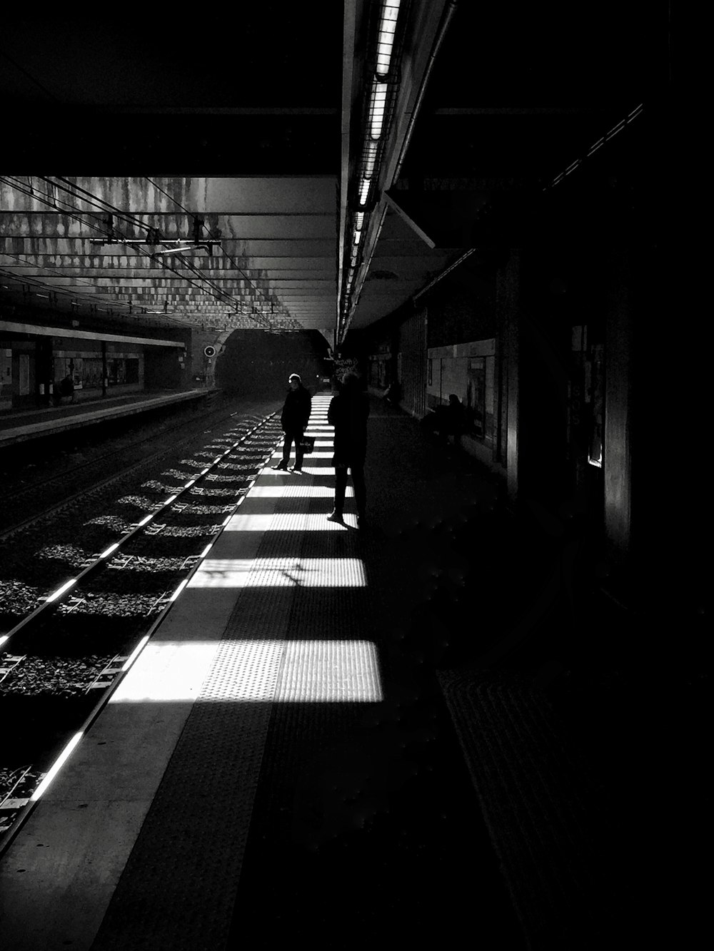 grayscale photo of man walking on train station