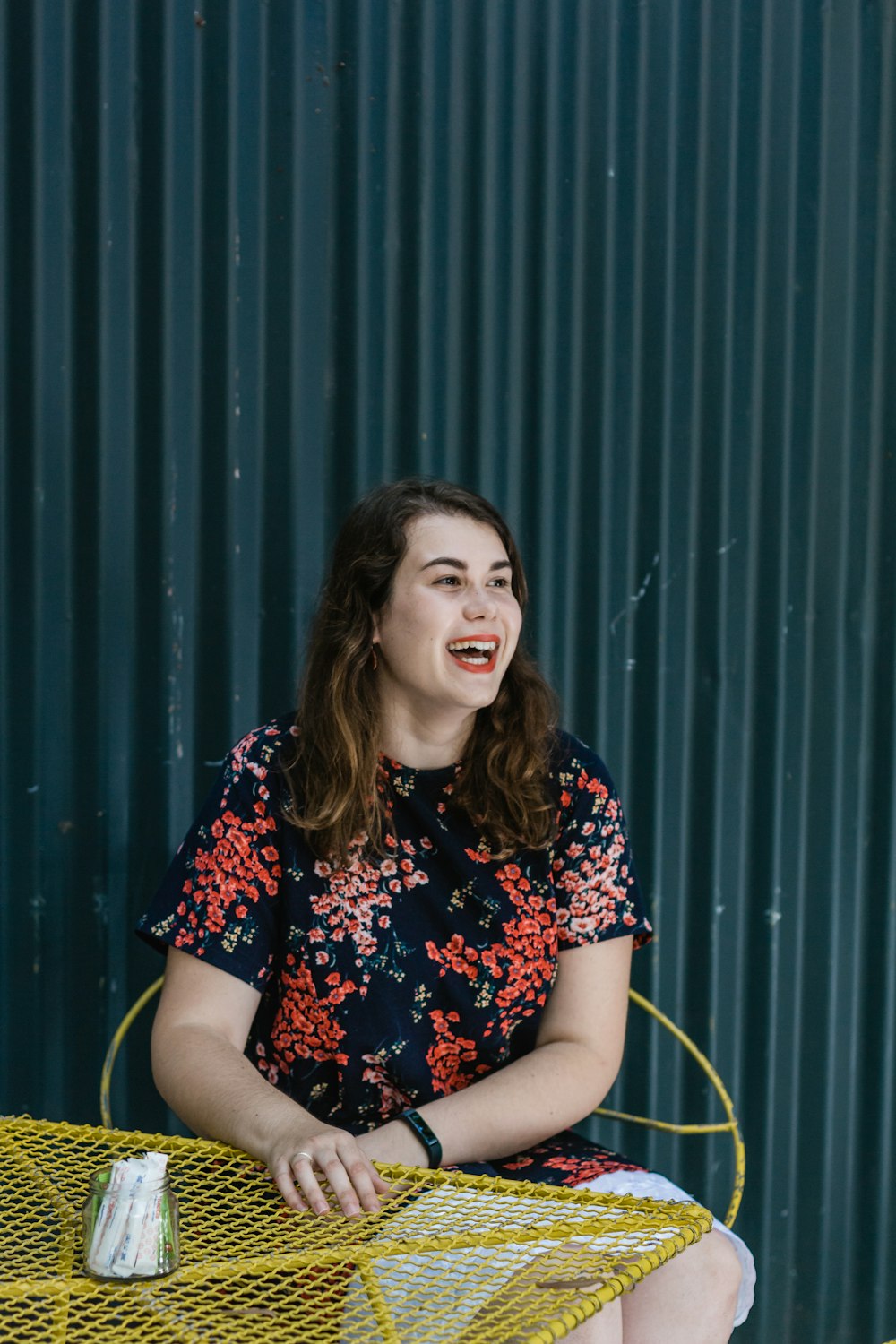 woman in blue and red floral shirt sitting on yellow chair