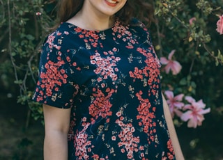 woman in blue and red floral dress standing near pink flowers