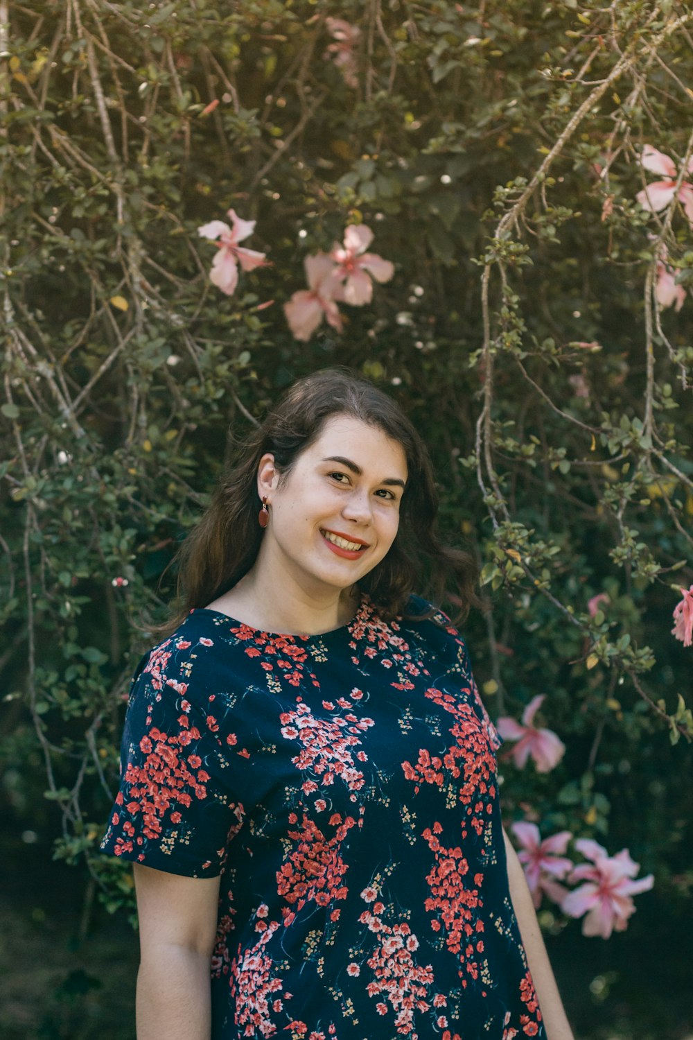 woman in blue and red floral dress standing near pink flowers