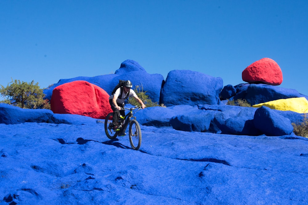 man in blue jacket riding on black mountain bike on white sand during daytime