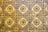 A geometric pattern of vintage floor tiles featuring floral motifs in earthy tones. The tiles are arranged in a repetitive diamond layout, with intricate flower designs at the center of each tile. The aged appearance of the tiles suggests historical or classical architecture.
