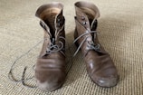 A stylish pair of men's leather boots resting on a rustic wooden floor.
