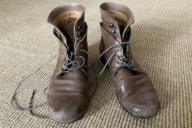 A pair of sleek leather boots resting on a rustic floor.