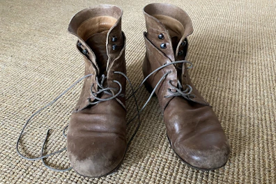 A pair of classic brown leather boots resting on a worn wooden floor.