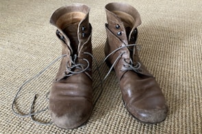 A stylish pair of men's leather boots resting on a rustic wooden floor.