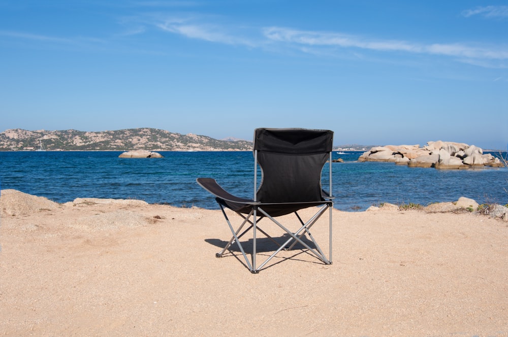cadeira dobrável preta e cinza na praia durante o dia