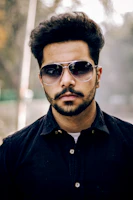 Stylish gentleman with a sharp haircut and subtle silver accents in the background.