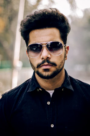 Stylish gentleman with a sharp haircut and subtle silver accents in the background.