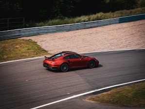 Close-up of a high-performance racing car speeding on a track during a sunny day.