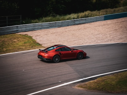 Close-up of a high-performance racing car speeding on a track during a sunny day.