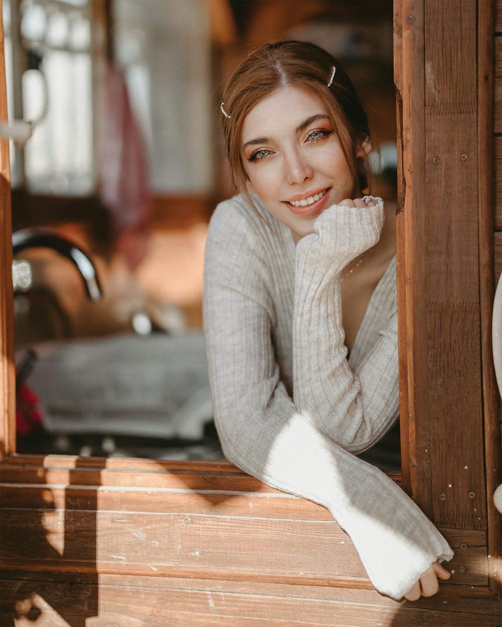 woman in gray sweater leaning on brown wooden wall