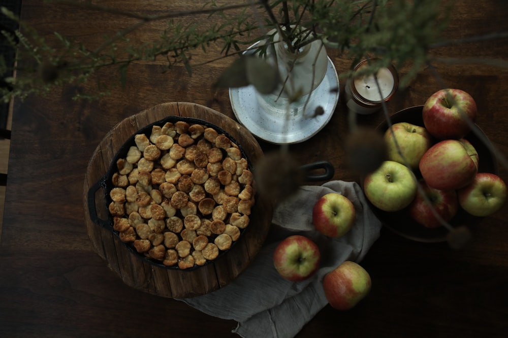 brown round food on brown wooden round bowl beside green apple fruit on brown wooden table